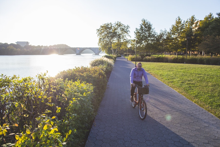 Man biking along the Potomac with the Lincoln Memorial in the background