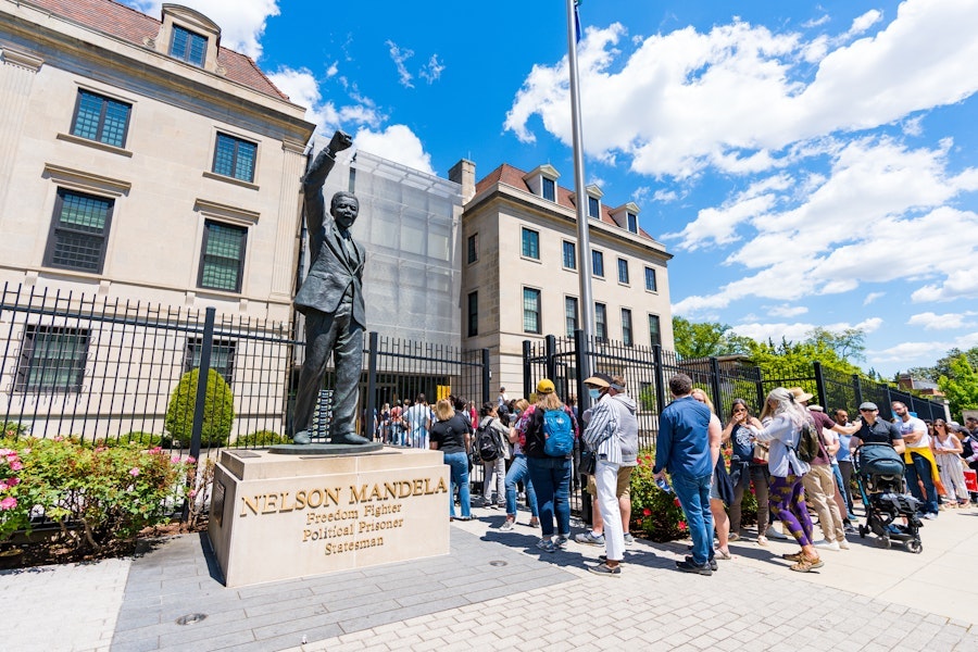 Visitors wait in line beside a statue of Nelson Mandela to enter the South African Embassy in Washington, DC. 