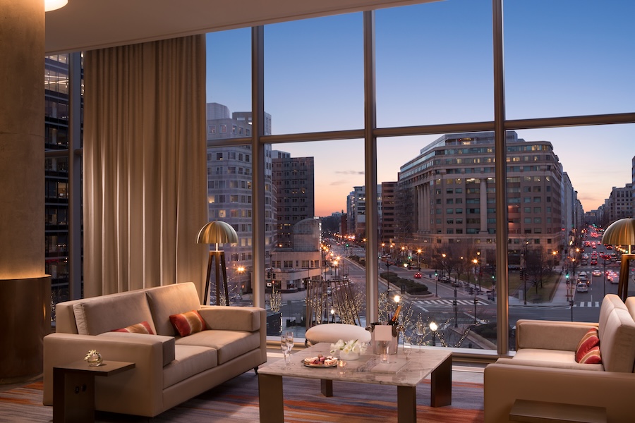 A chic seating area with bites and champagne, plus full-length windows looking out on to a DC street at dusk. 