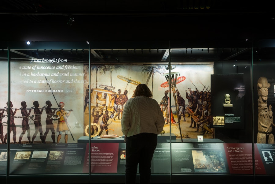 A museum-goer peers into glass cases with information on the slave trade in the U.S.