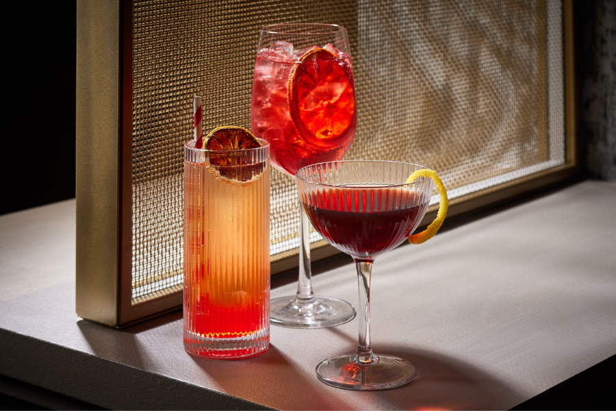 Three vibrant cocktails with citrus garnishes on a softly lit table in Washington, DC.