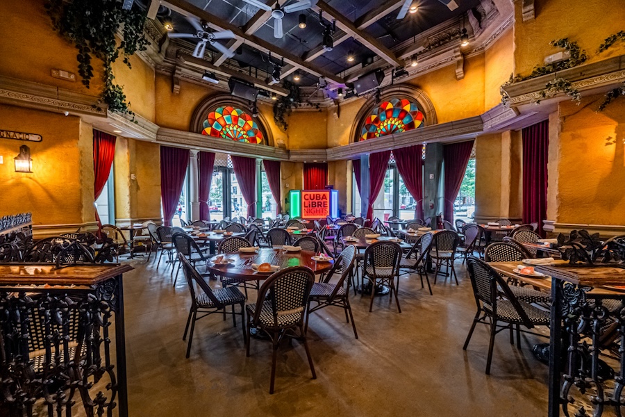 Interior of Cuba Libre Restaurant with colorful stained glass, dramatic curtains and arranged dining tables.