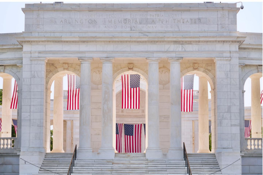 The marble Arlington Memorial Amphitheater adorned with American flags for a patriotic ceremony.