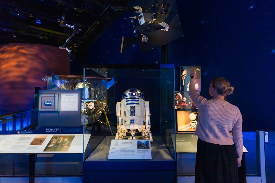 A visitor points at a Star Wars-themed exhibit featuring R2-D2 at the National Air and Space Museum.