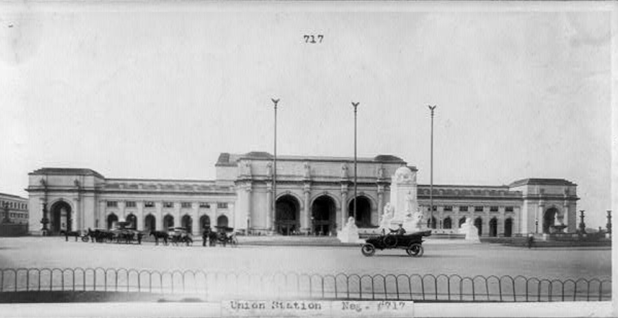 Early 20th-century photo of Union Station in Washington, DC, with horse-drawn carriages and an early automobile in front.
