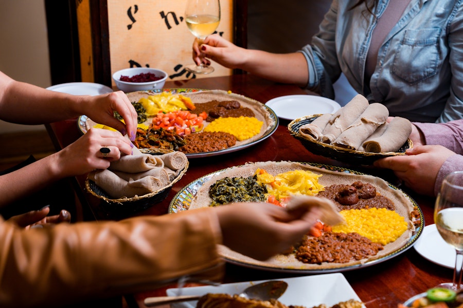 A colorful spread of Ethiopian dishes featuring injera, stews and fresh vegetables.