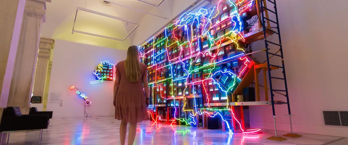 A woman poses in front of a large, bright display of colorful lights, showcasing a lively scene.